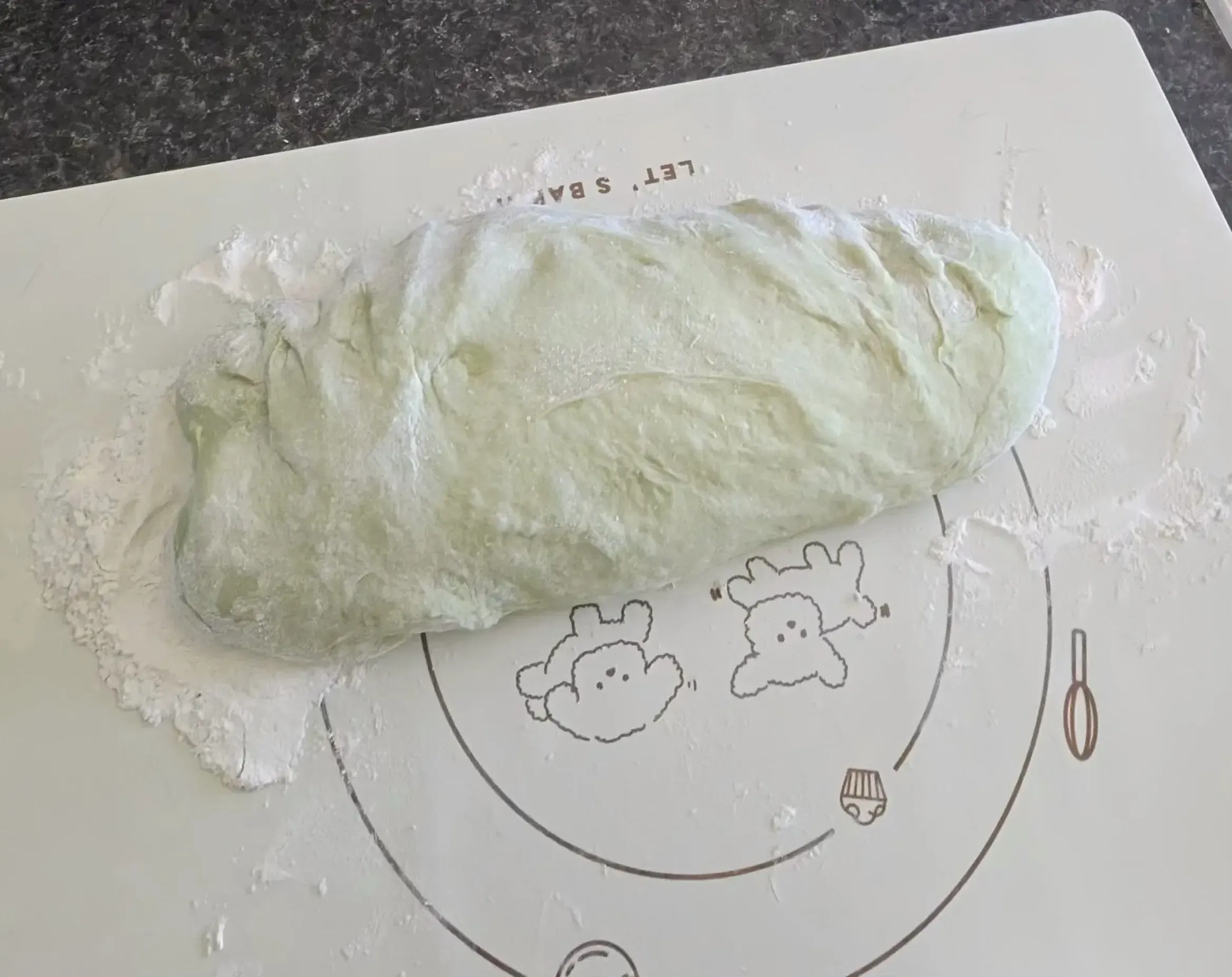 Green dough shaped into a log on baking mat