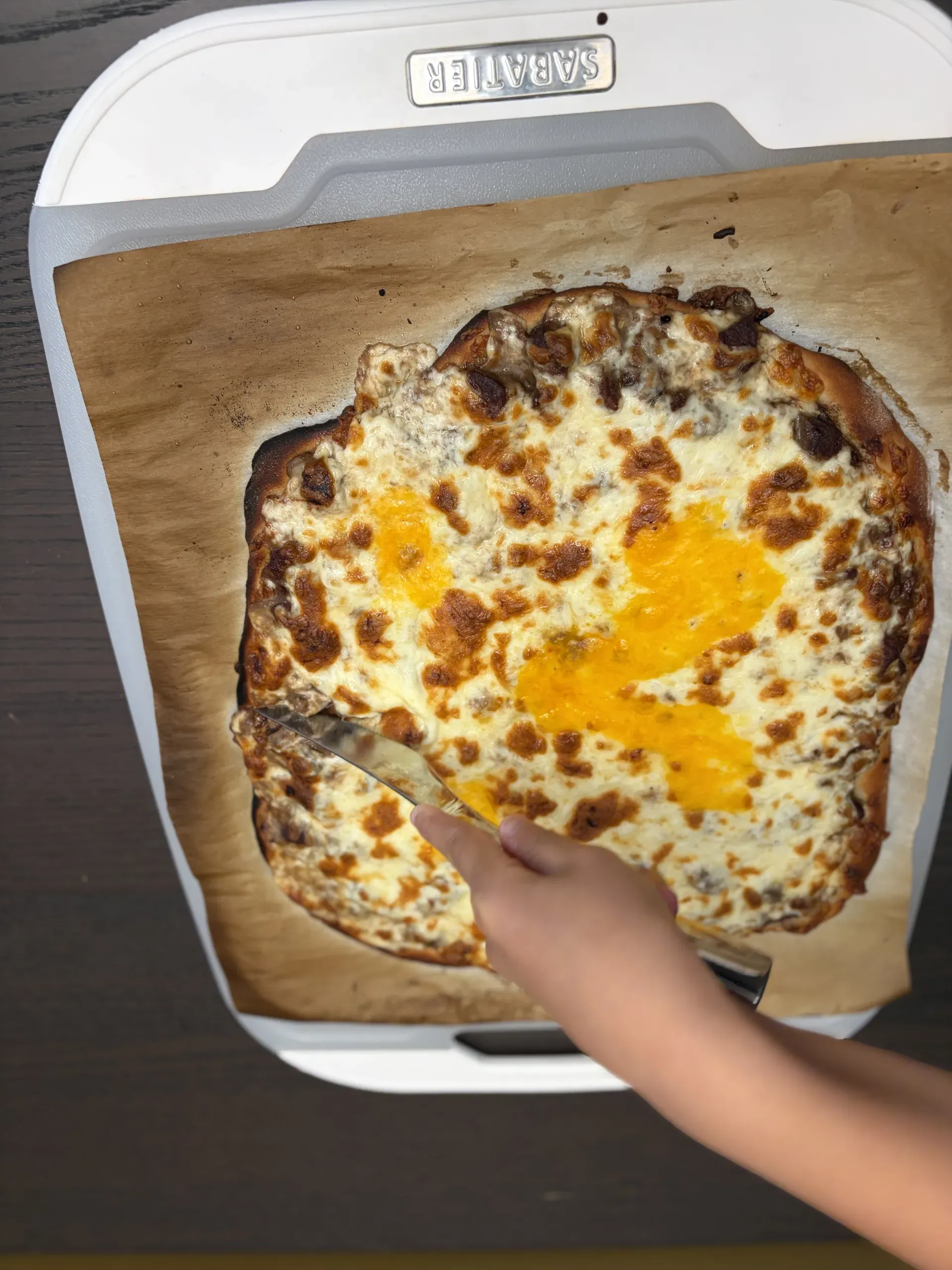 A child carefully slicing into the hot homemade pizza on the cutting board
