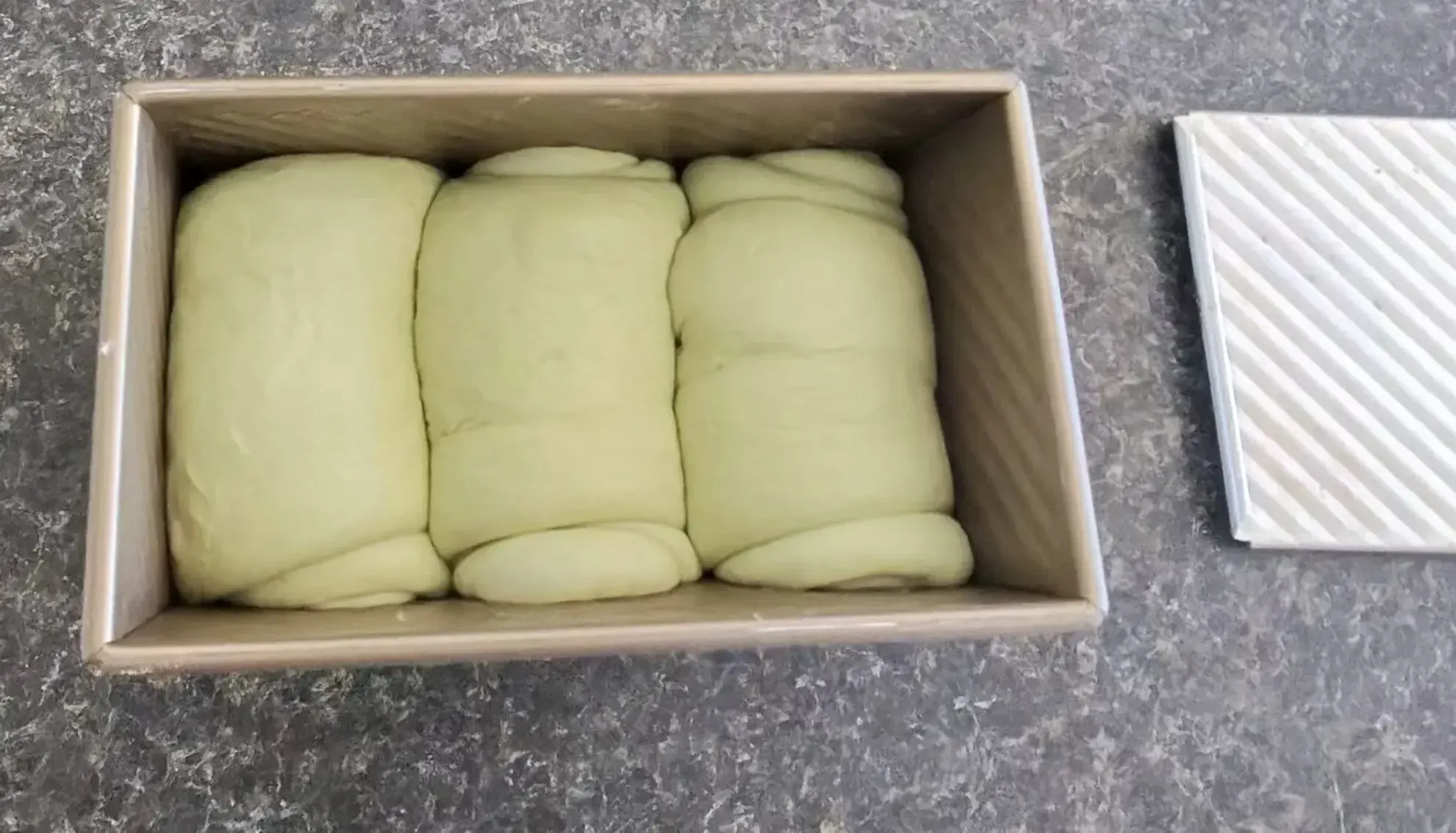 Three rolled dough portions resting inside the Pullman tin